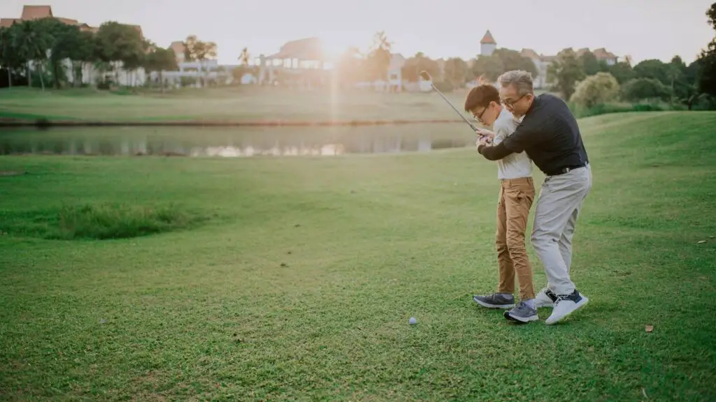 Father teaching son how to play golf