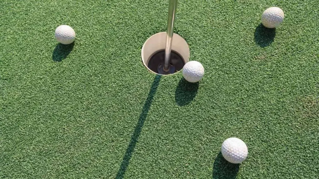 Four balls lying around golf hole on golf green