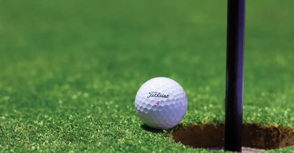 Golf ball falling into golf hole on green