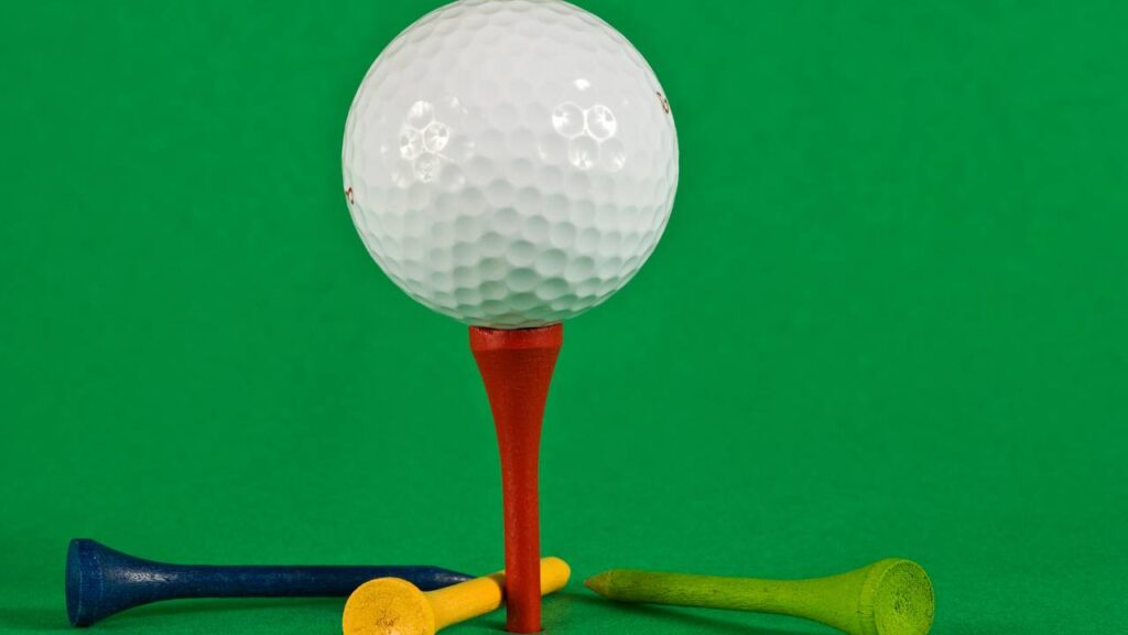 Golf ball on golf tee in front of green screen