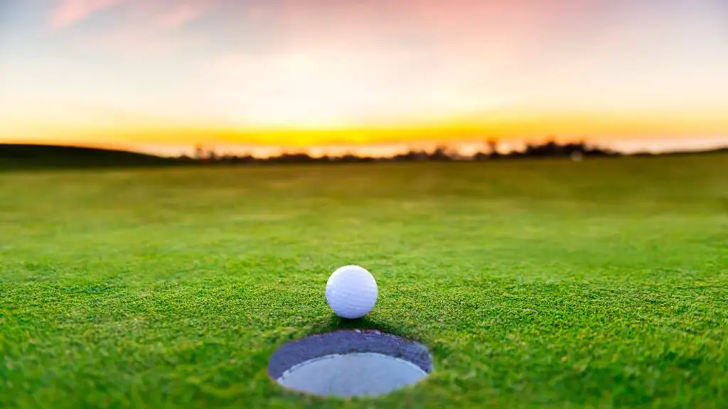Golf ball sitting on edge of golf hole