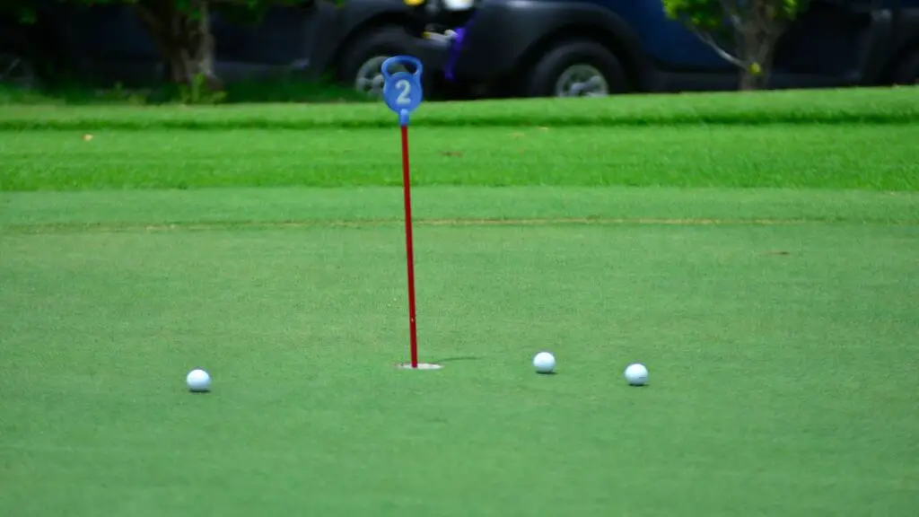 Golf balls lying on golf green next to hole