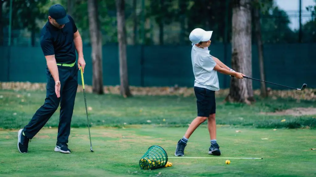 Golf instructor showing young golfer how to swing