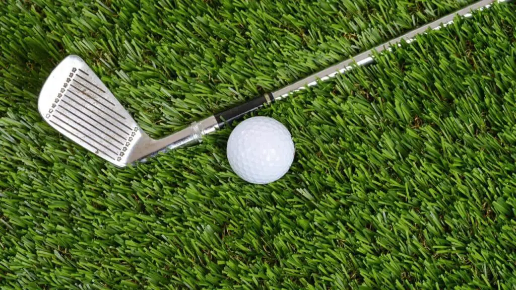 Golf wedge and golf ball on green grass