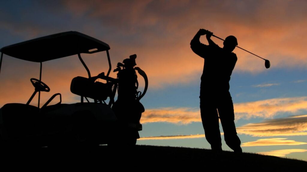 Golfer hitting shot sunset