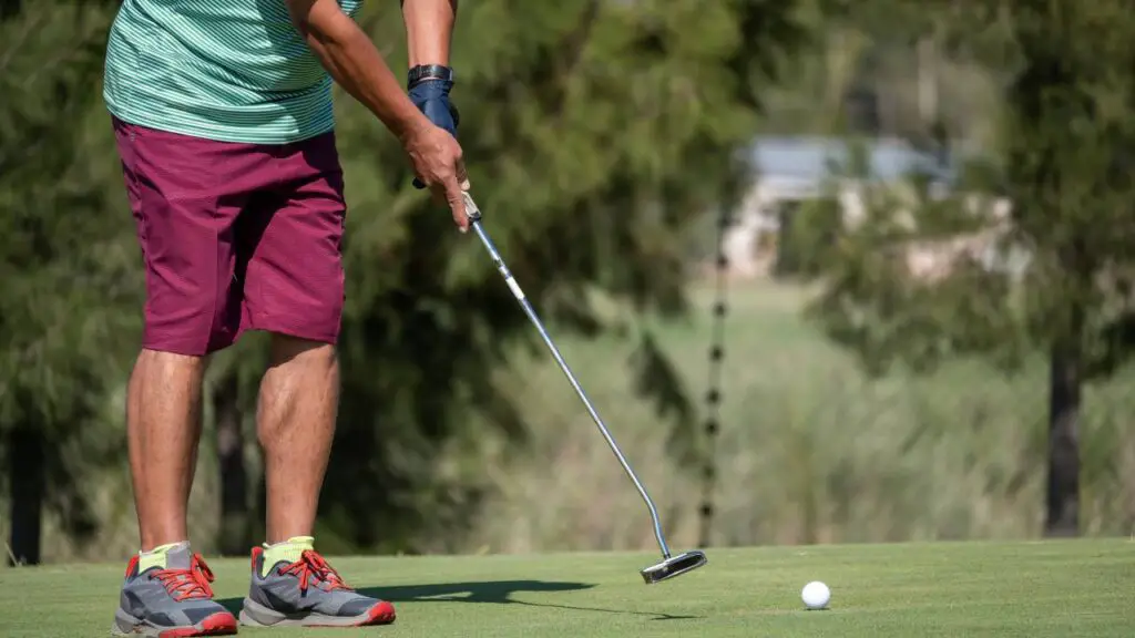 Golfer putting golf ball on golf green