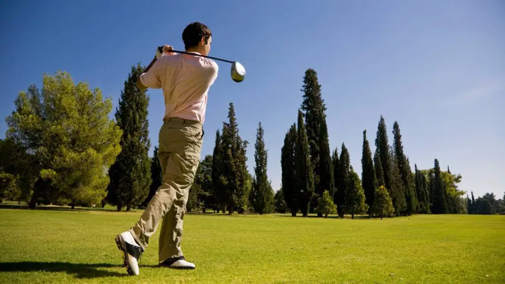 Golfer swinging shot off tee showing moment of innertia