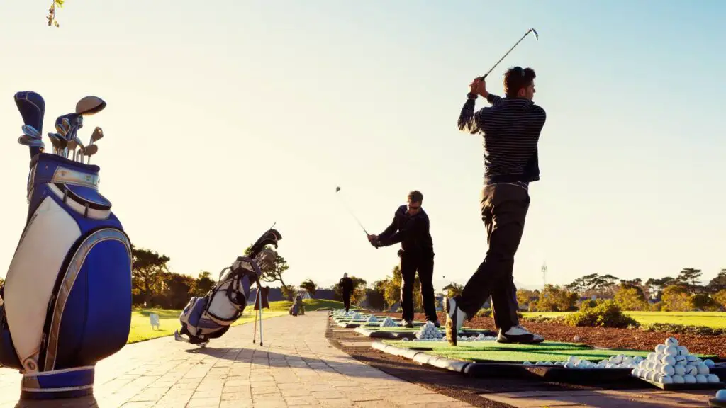Golfers swinging golf balls on driving range