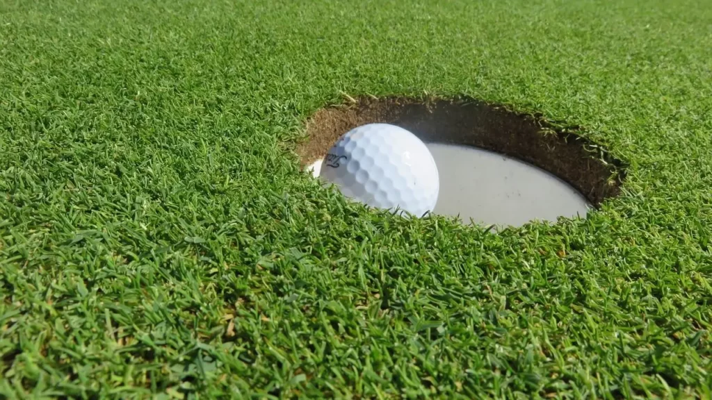 Golf ball going into golf hole