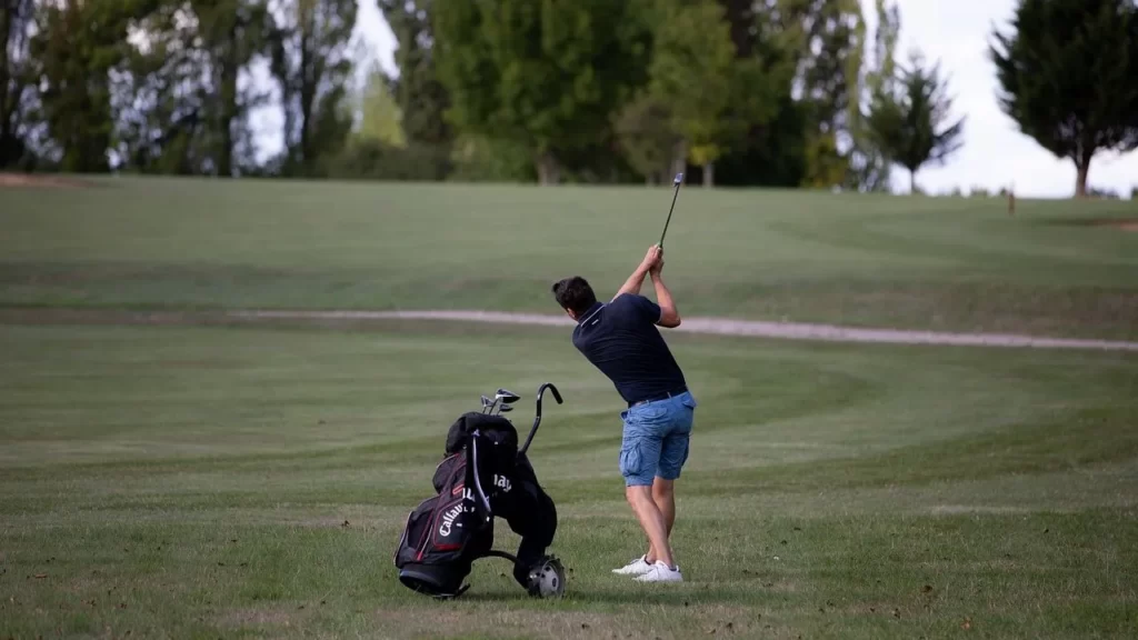 Golfer swinging at a golf ball on golf course