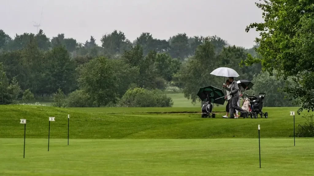 Golfer playing golf in the rain with an umbrella
