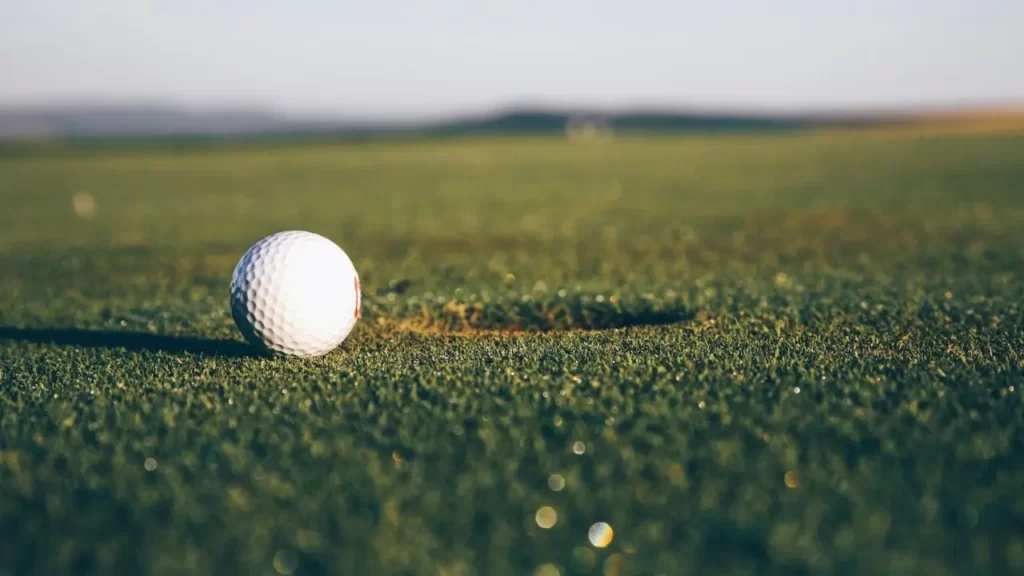 Golf ball near golf hole on golf course