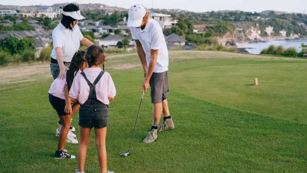 Father showing kids how to hit golf ball