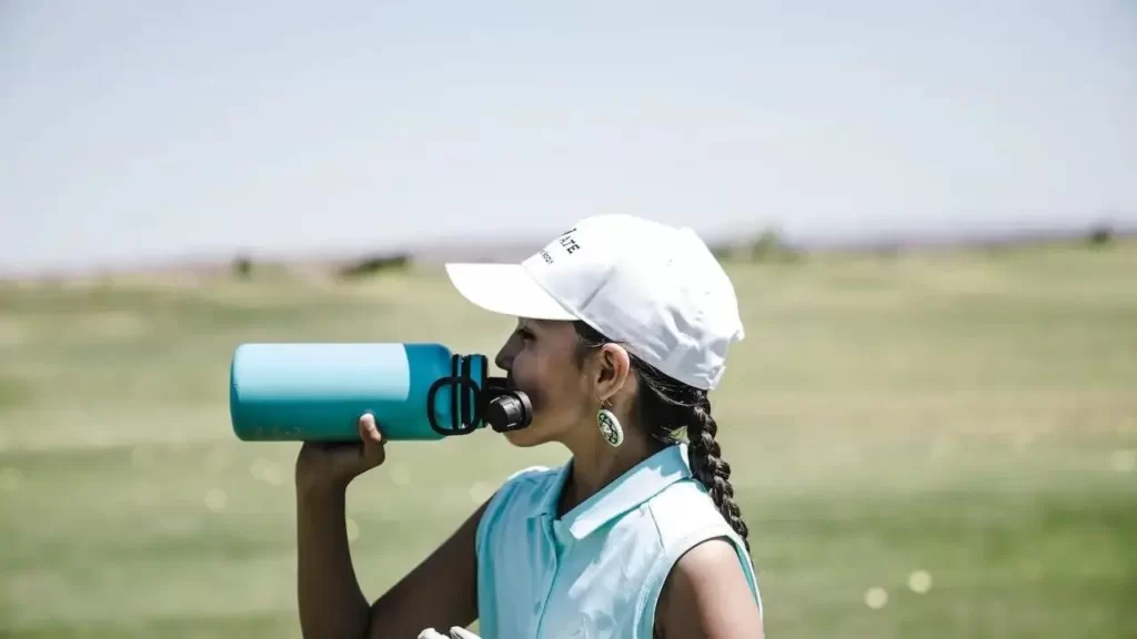 Female golfer drinking water on golf course