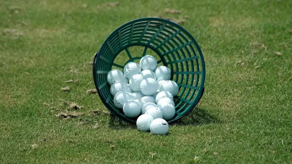 Golf balls in a basket fallen over on golf course