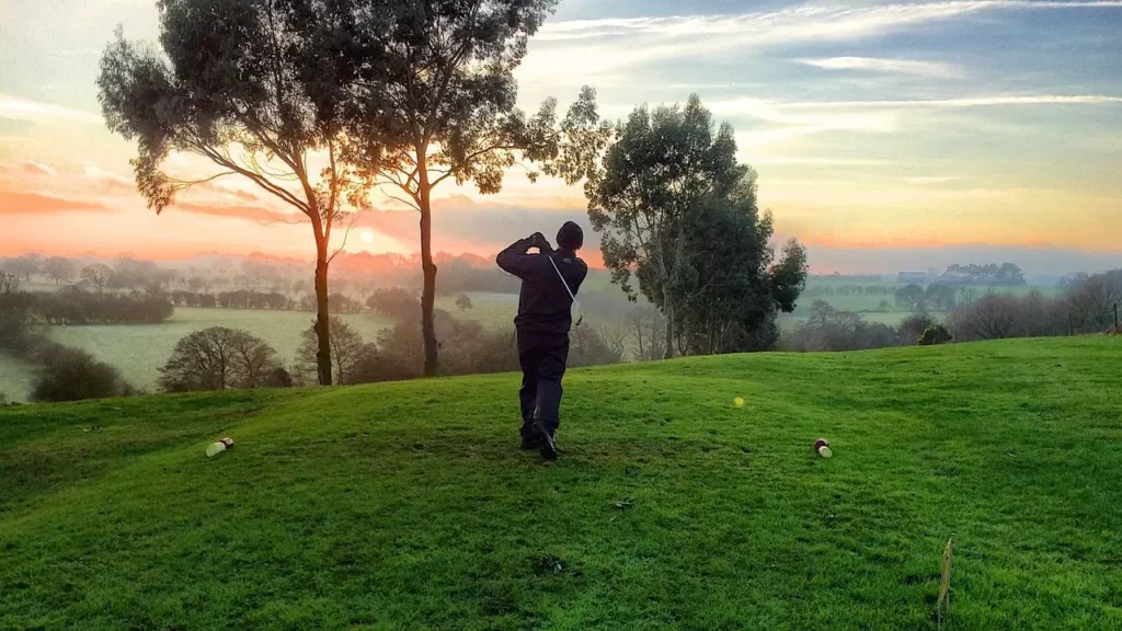 Golfer teeing up golf swing on golf course