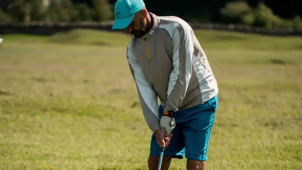 Golfer wearing hat and shorts lining up shot
