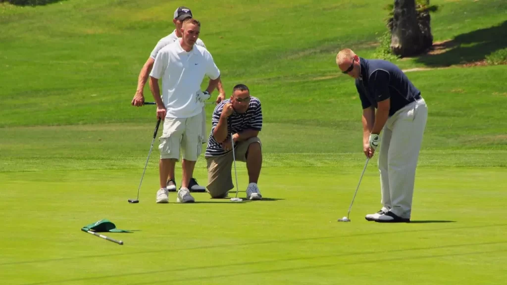 Group of golfers spectating putt