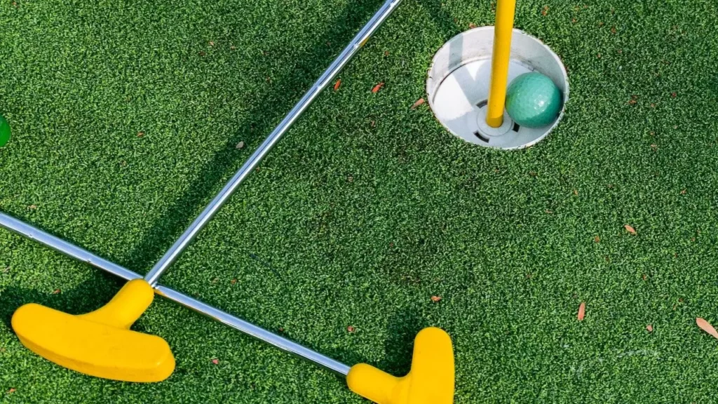 Golf clubs lying on golf course around hole