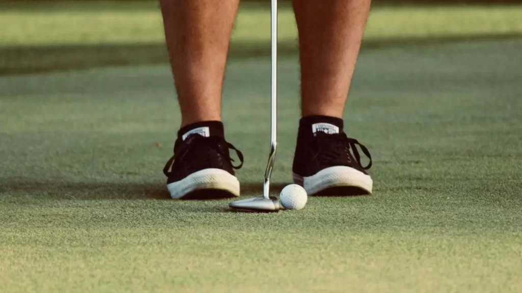 Golfer putting ball using black shoes