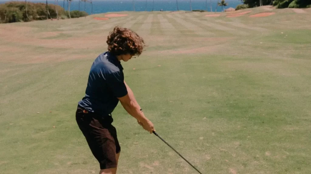 Boy hitting golf ball on golf course