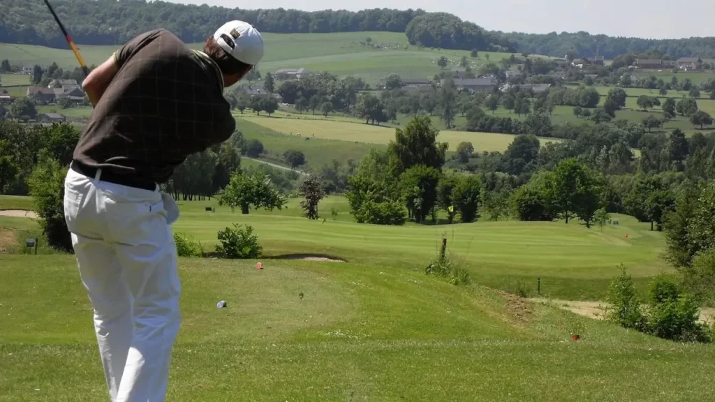 Golfer hitting tee shot wearing white pants