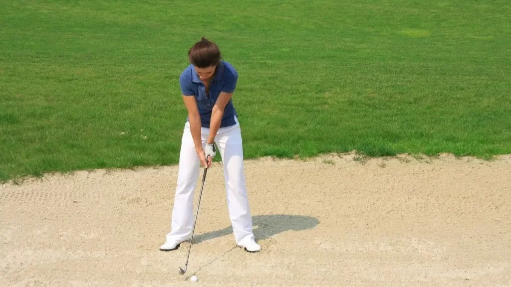 Female golfer hitting shot out of bunker