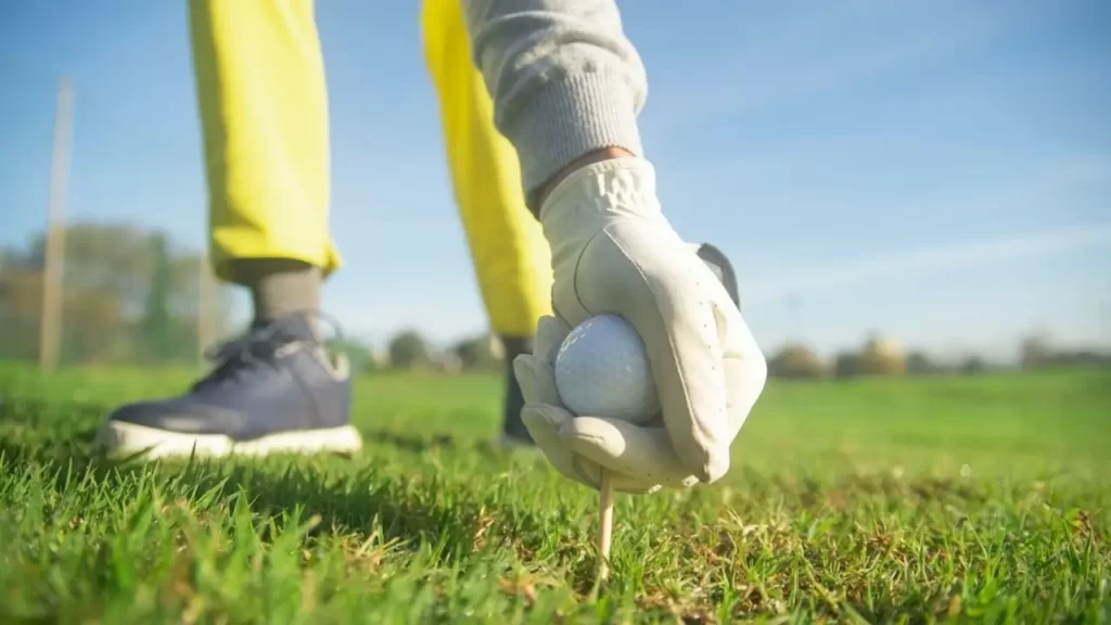 Golfer using a regular golf glove placing a ball on a golf tee