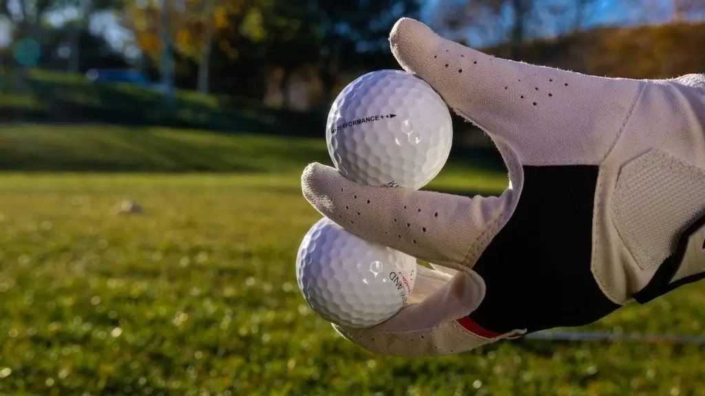 Golfer wearing a cadet golf glove juggling golf balls on golf green