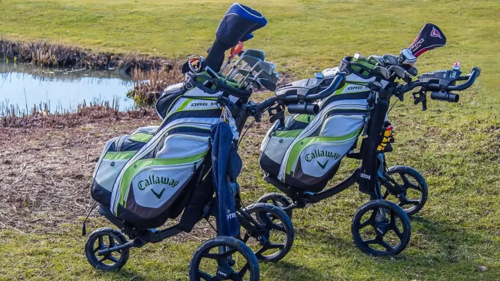 Golf caddy bags sitting on golf green with golf clubs