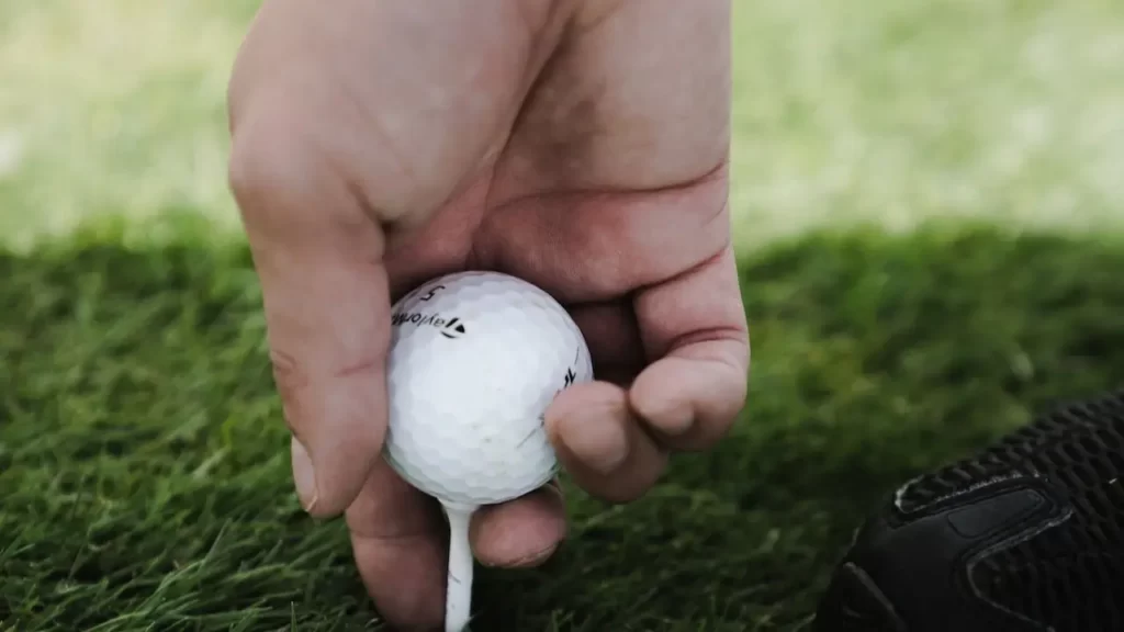 Golfer placing golf ball on golf tee