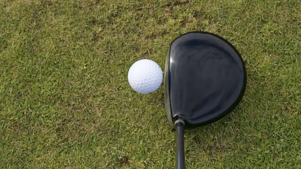 A golf driver viewed from above hitting a white golf ball