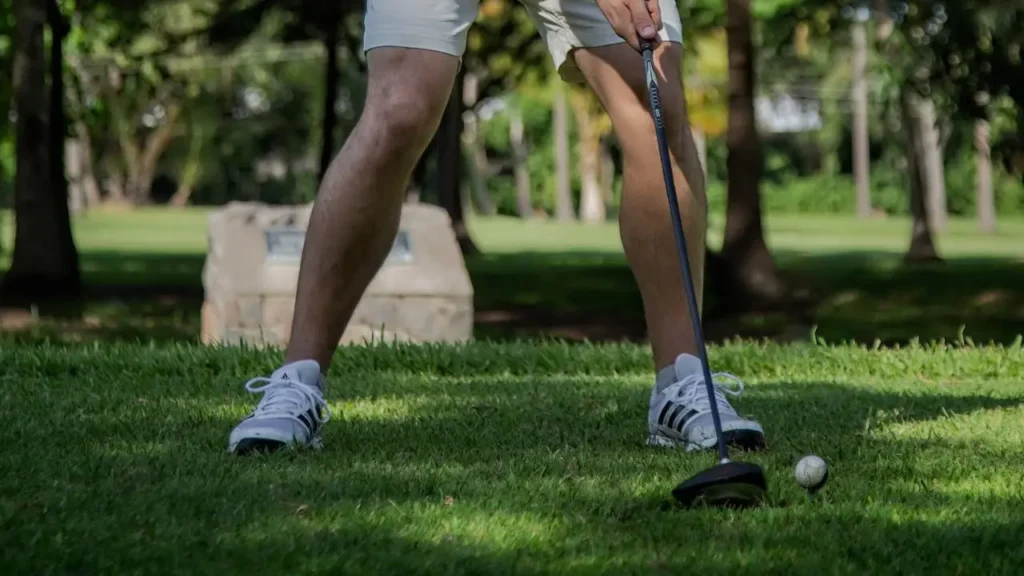 A golfer hitting a golf ball with a golf iron