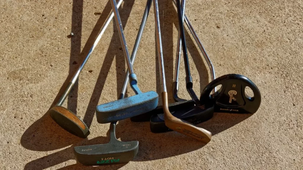 A bunch of old rusted golf clubs on the floor