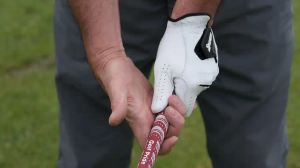A golfer holding a golf club with a red and white grip