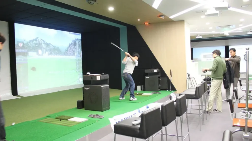 Golf simulator with screen and man playing golf