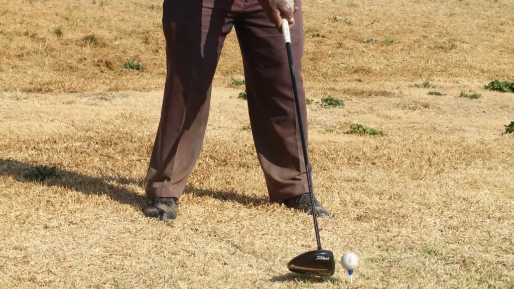 A golfer lining up a golf shot with a wood golf club