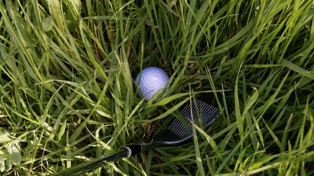 A 52 degree golf wedge hitting a golf ball out of the weeds on a golf course