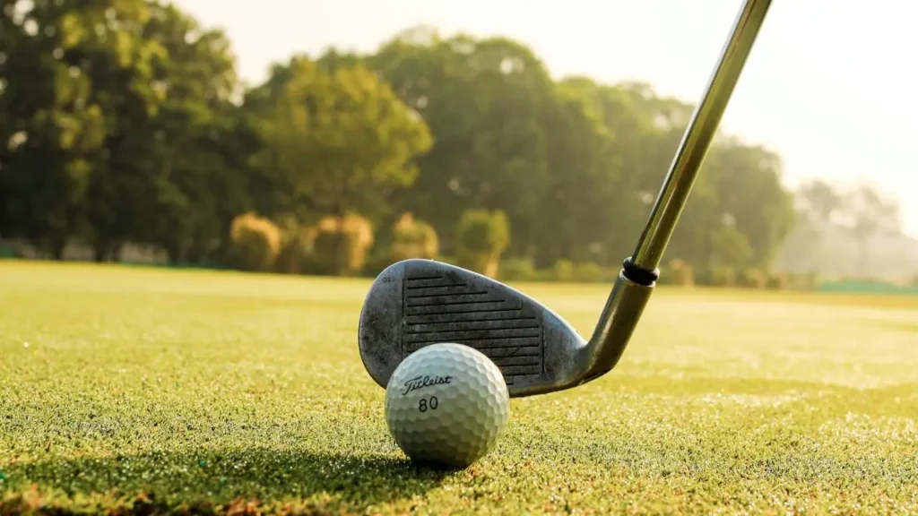 A white golf ball with a golf wedge behind it