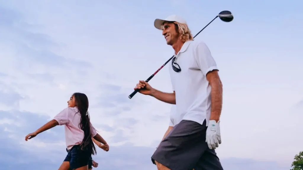 A golfer walking on a golf course holding a golf club