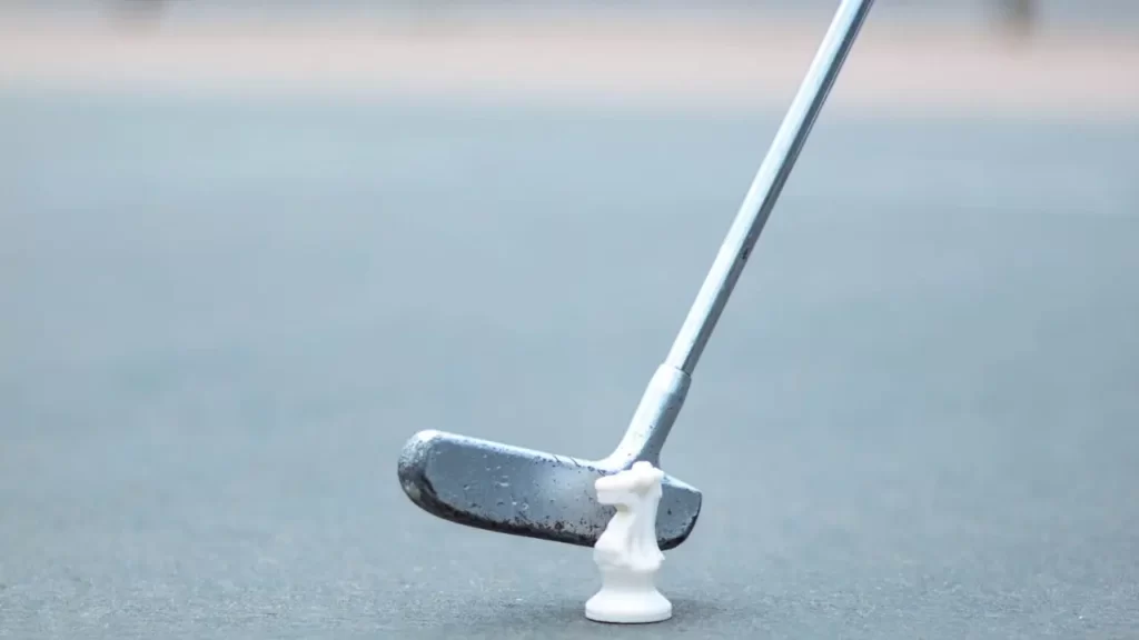 A golf club being lined up to hit a chess piece
