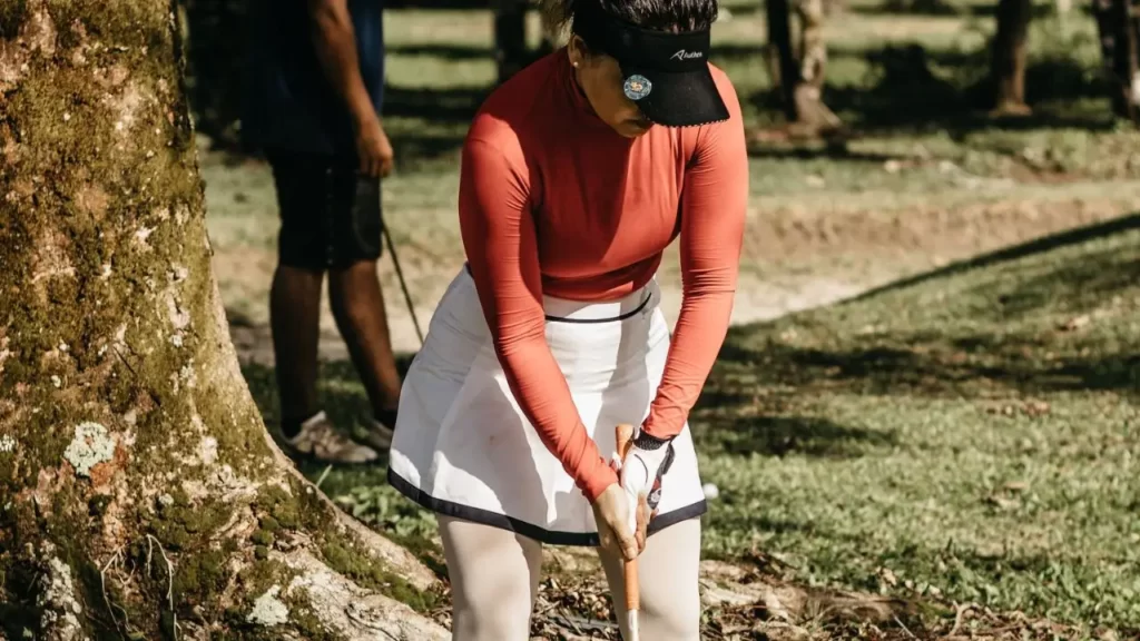 A female golfer holding a golf club ready to putt a shot