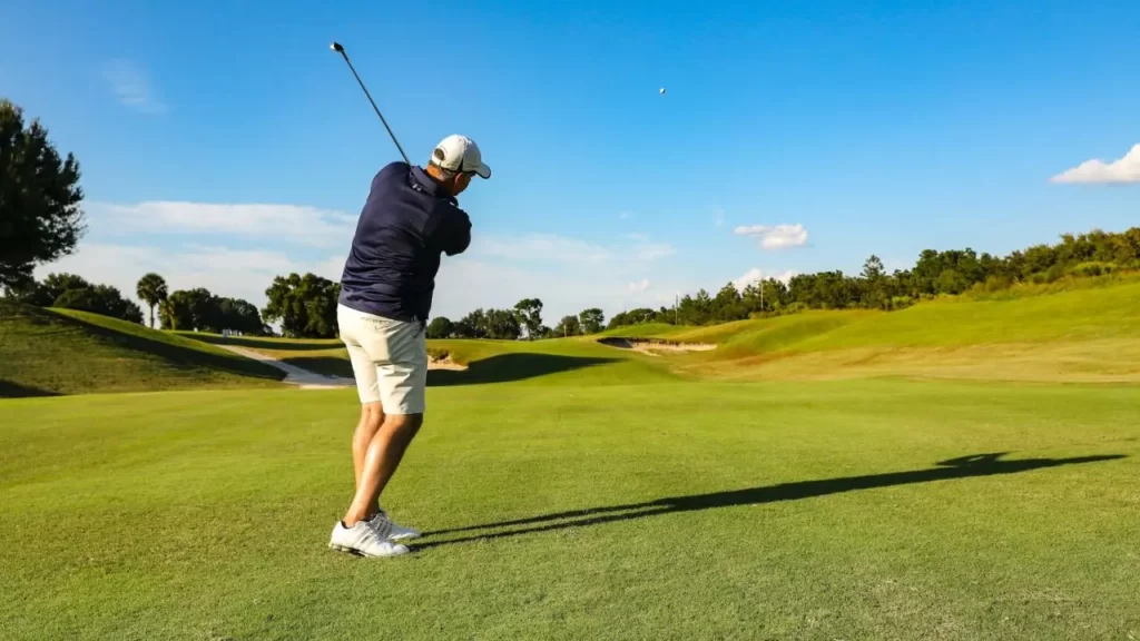 Golfer swinging golf tee shot on golf course