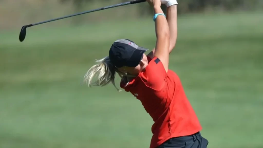 Female golfer swinging a golf shot on golf course