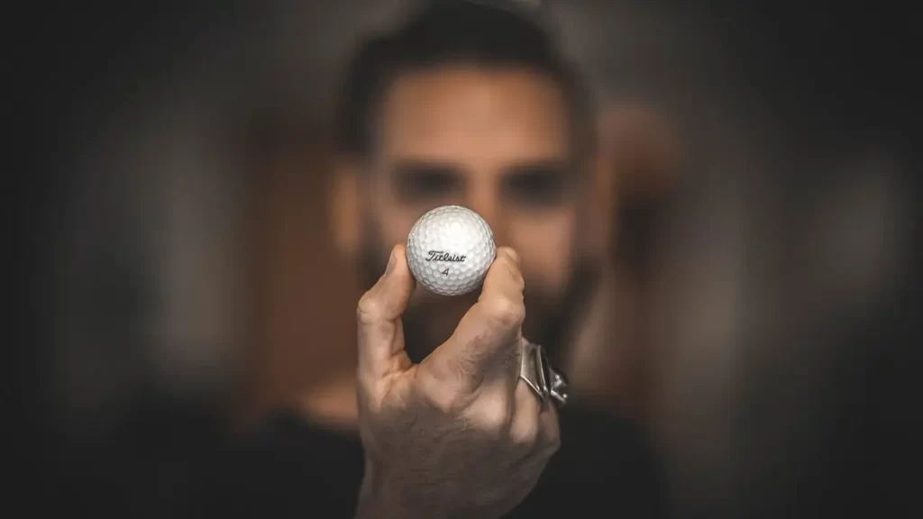 A person holding up a golf ball in their hand