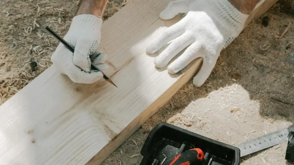 A worker measuring a wooden plank to be cut
