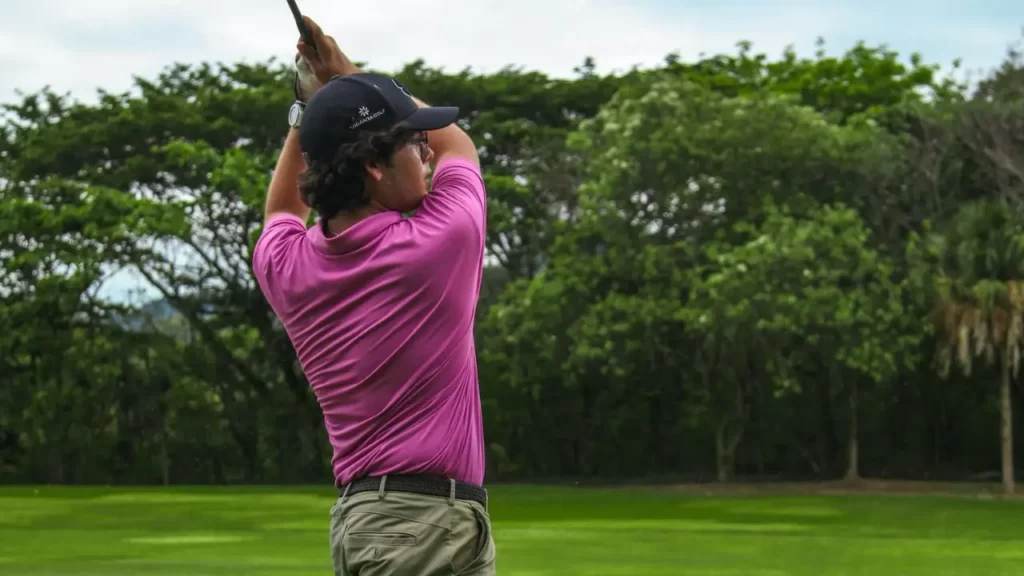 Golfer wearing purple shirt hitting a golf shot