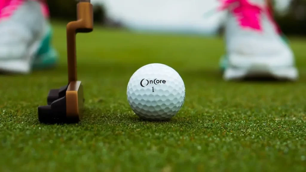 A golf ball sitting on a golf course green about to be hit by a golf club