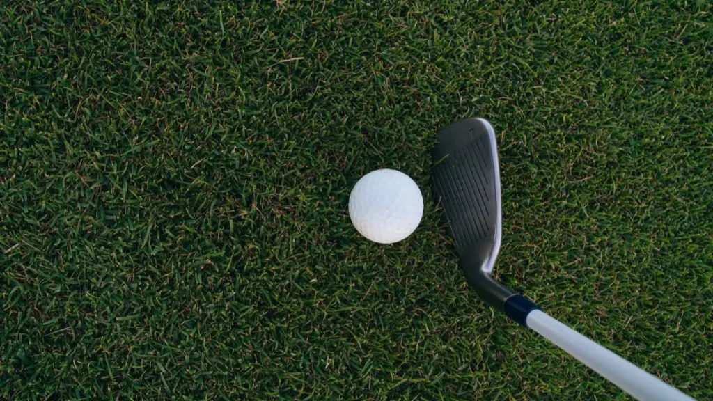 A top of view of a golfer hitting a golf ball with a golf club iron