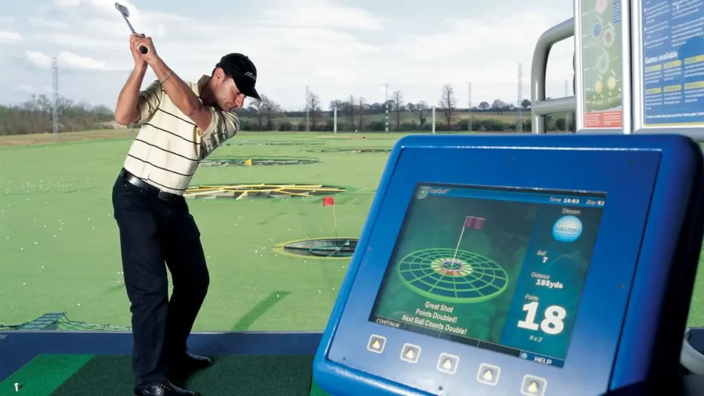 Golfer swinging at a golf simulator and screen